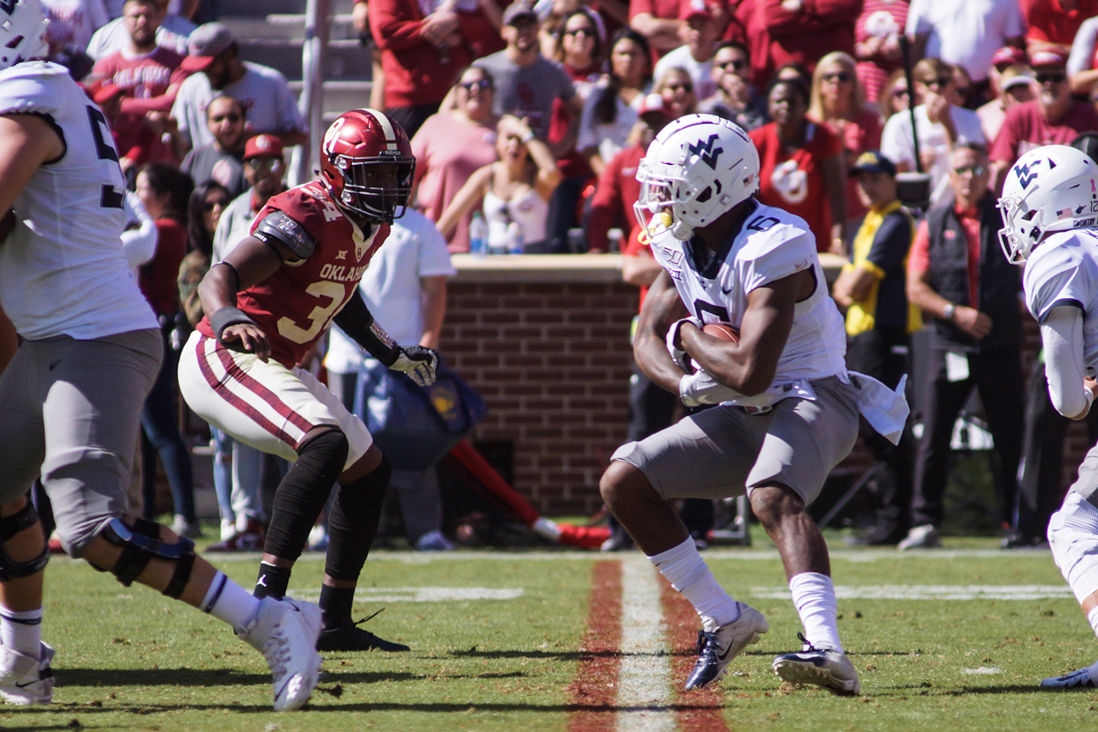 West Virginia running back Kennedy McKoy (right) takes the handoff from Austin Kendall against Oklahoma at Oklahoma Memorial Stadium on October 19, 2019.